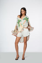 Woman wearing a tropical-themed cover-up with palm trees on a white background