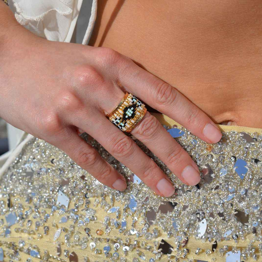 Close-up of a hand wearing a decorative ring on a glittery surface