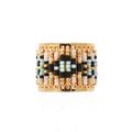 Beaded ring with gold, black, and white beads on a white background
