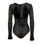 Black lace long-sleeve bodysuit shown from the back, featuring a large open back with a black satin bow tie detail, on a solid white background.