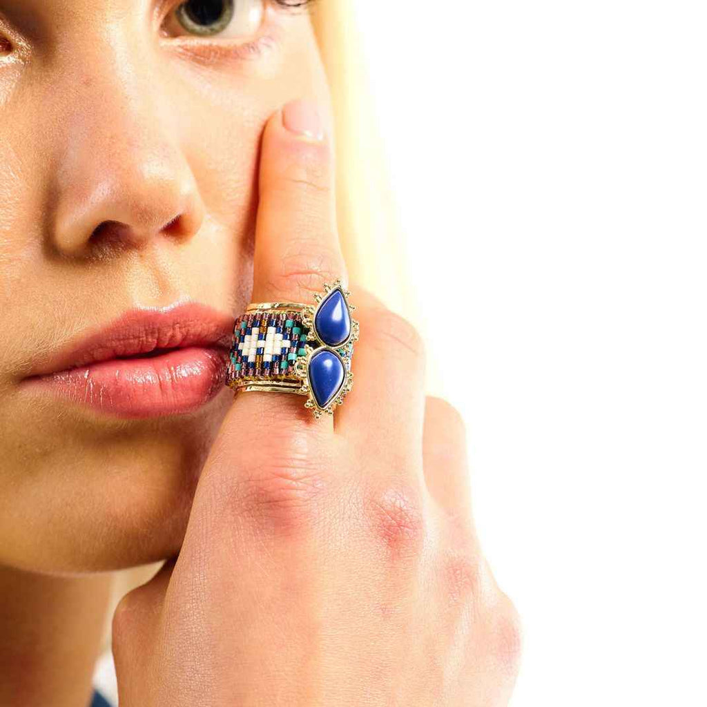 Close-up of a woman's hand wearing a decorative ring with blue stones on a white background
