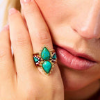 Close-up of a hand wearing a turquoise gemstone ring with gold accents.