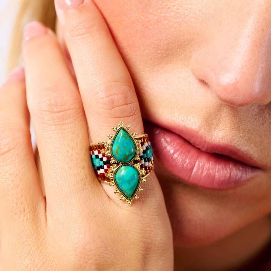 Close-up of a hand wearing a turquoise gemstone ring with gold accents.