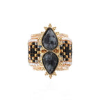 Gold and black checkered bracelet with teardrop-shaped stones on a white background