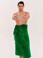 Man wearing a green towel around his waist on a plain background