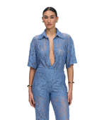 A model wearing a light blue lace short-sleeve jumpsuit with a deep V-neckline, photographed against a solid white background.