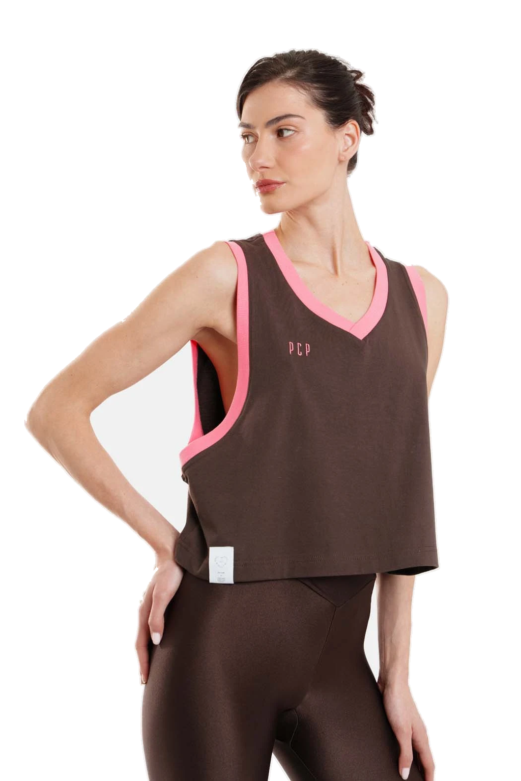 A woman modeling a brown athletic tank top with bright pink trim and matching brown leggings against a plain white background.
