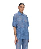 A model wearing a matching blue lace short-sleeve button-up shirt and pants set, photographed against a solid white background.