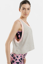 Woman wearing a gray tank top with pink trim and pink leggings with black patterns on a white background