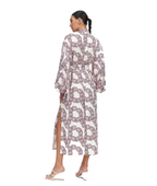 A woman shown from the back wearing a long-sleeved maxi dress with a high side slit, featuring an all-over chain-link print in muted mauve and white. She is wearing white strappy flat sandals against a solid white background.
