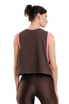 A woman shown from the back wearing a dark brown sleeveless crop top with bright pink trim and matching dark brown leggings against a plain white background.
