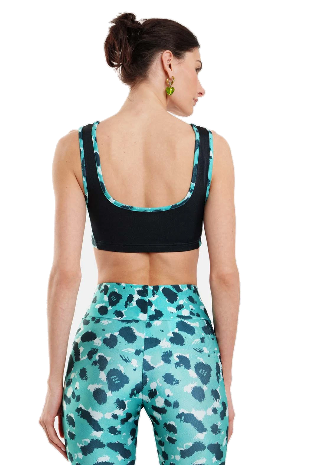 A woman shown from the back wearing a black sports bra with teal and white patterned trim, paired with matching teal and black patterned leggings, against a plain white background.