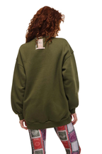 A person shown from the back wearing an oversized olive green sweatshirt and colorful patterned leggings against a plain white background.