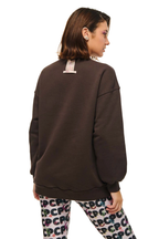 A woman shown from the back wearing an oversized dark brown sweatshirt and patterned leggings with the letters 'PCP' repeated across them, against a plain white background.