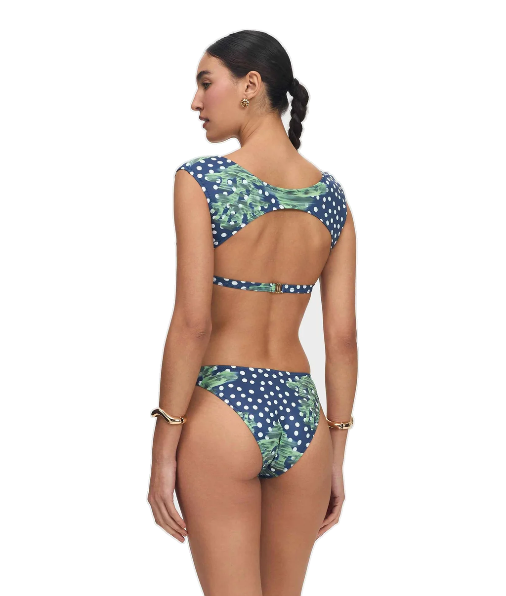 A woman modeling a two-piece bikini from the back, featuring a navy blue and white polka dot pattern with green tropical leaf prints, set against a plain white background.