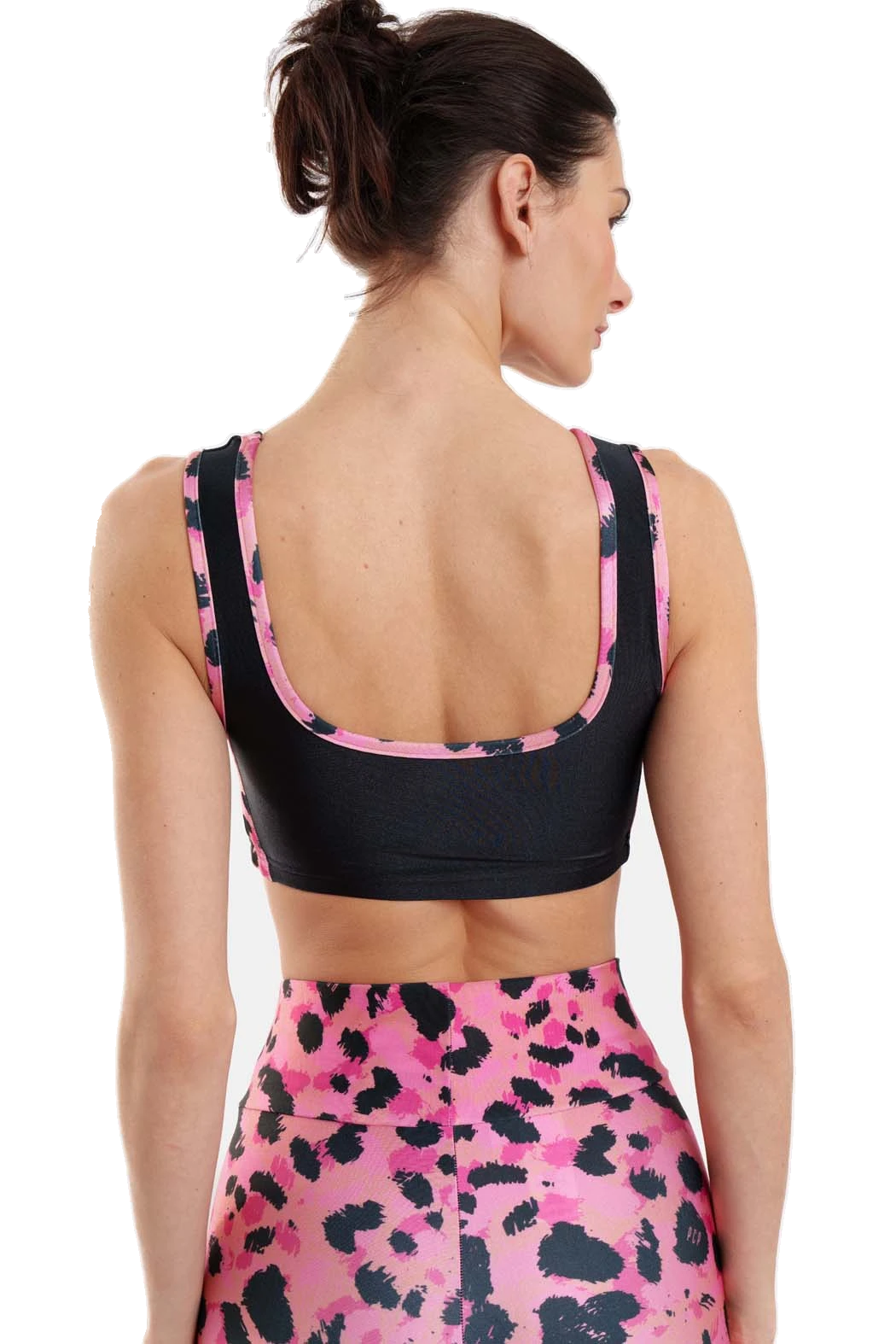 A woman shown from the back wearing a black sports bra with pink and black patterned trim and a matching pink high-waisted leggings with a black animal print, against a plain white background.