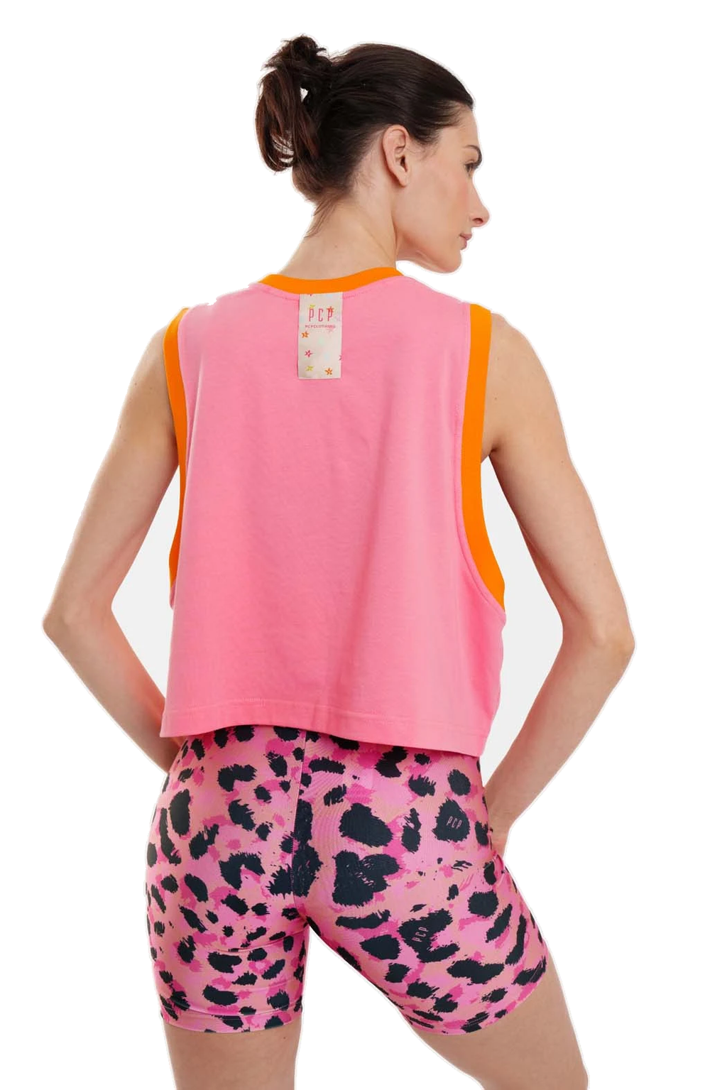 A woman shown from the back wearing a bright pink sleeveless crop top with orange trim and pink leopard-print biker shorts against a plain white background.
