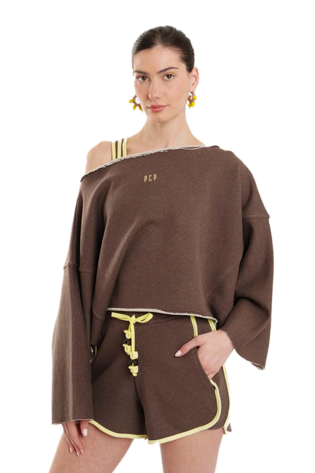 A model wearing a brown off-the-shoulder long-sleeve top and matching brown shorts with yellow contrast piping and drawstring details, photographed against a solid white background.