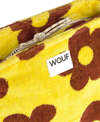 Close-up of a yellow and brown floral patterned textile item with a white zipper and a white label reading WOUF.