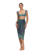 A woman modeling a matching two-piece sarong set featuring a green and navy blue paisley print with white polka dots, consisting of a crop top and a high-waisted wrap skirt, shot against a solid white background.